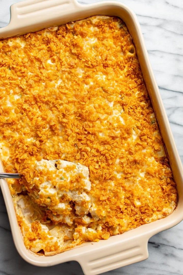 Beerdigungskartoffeln 8 Eine Auflaufform mit käsigen Funeral Potatoes und einem Servierlöffel