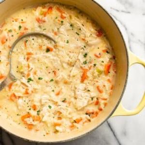 Cremige Hühner-Reis-Suppe 9 Nahaufnahme eines Topfes mit cremiger Hähnchen-Reis-Suppe und einer Schöpfkelle.