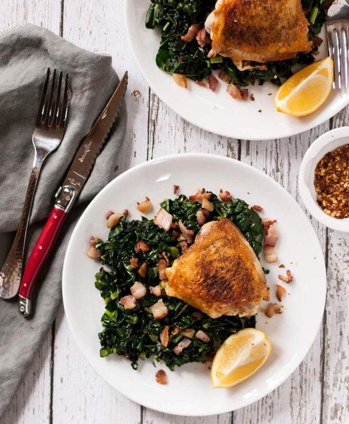 crispy chicken thighs with garlicky kale on a plate with knife and fork