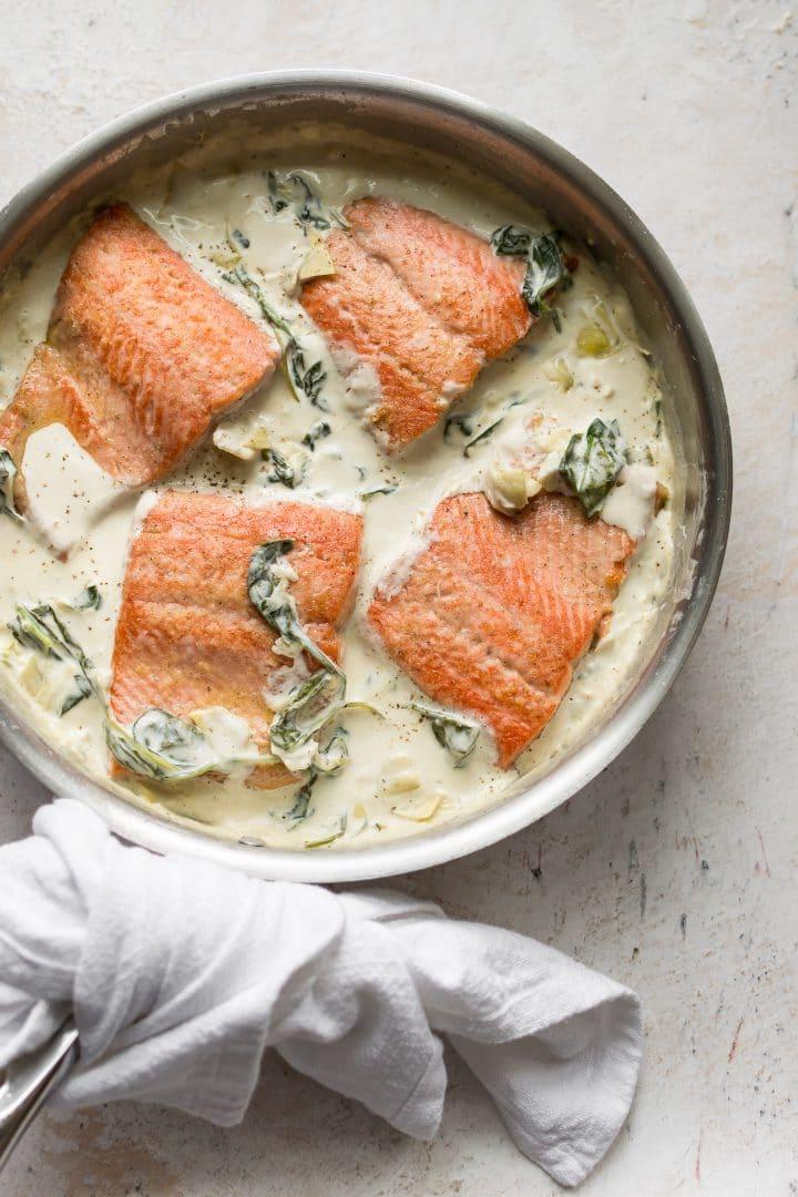 Lachs mit Spinat und Artischocken in einer Pfanne