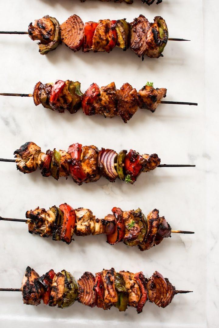 Mehrere gegrillte Hähnchenspieße mit roten Zwiebeln, grünen und roten Paprika