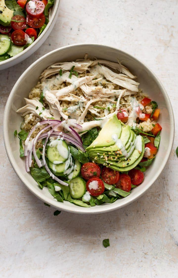 Zwei weiße Schüsseln mit einfach zuzubereitendem und gesundem Ranch Hähnchen-Quinoa-Salat, appetitlich angerichtet und bereit zum Servieren.