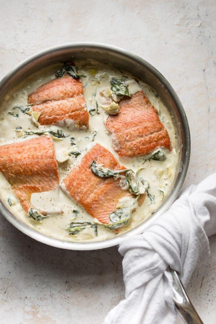 Lachs in einer cremigen Spinat- und Artischockensauce in einer Pfanne