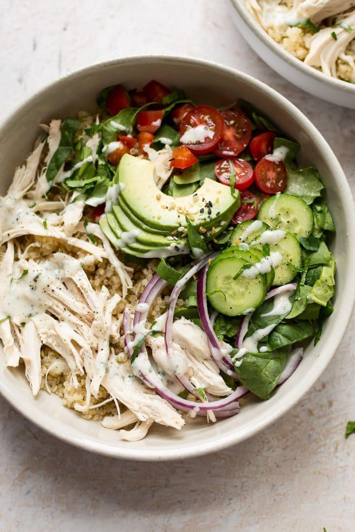 Weiße Schüssel mit Hähnchen-Quinoa-Salat, zubereitet mit übrig gebliebenem Hähnchenfleisch, was die Zubereitung besonders schnell und einfach macht.
