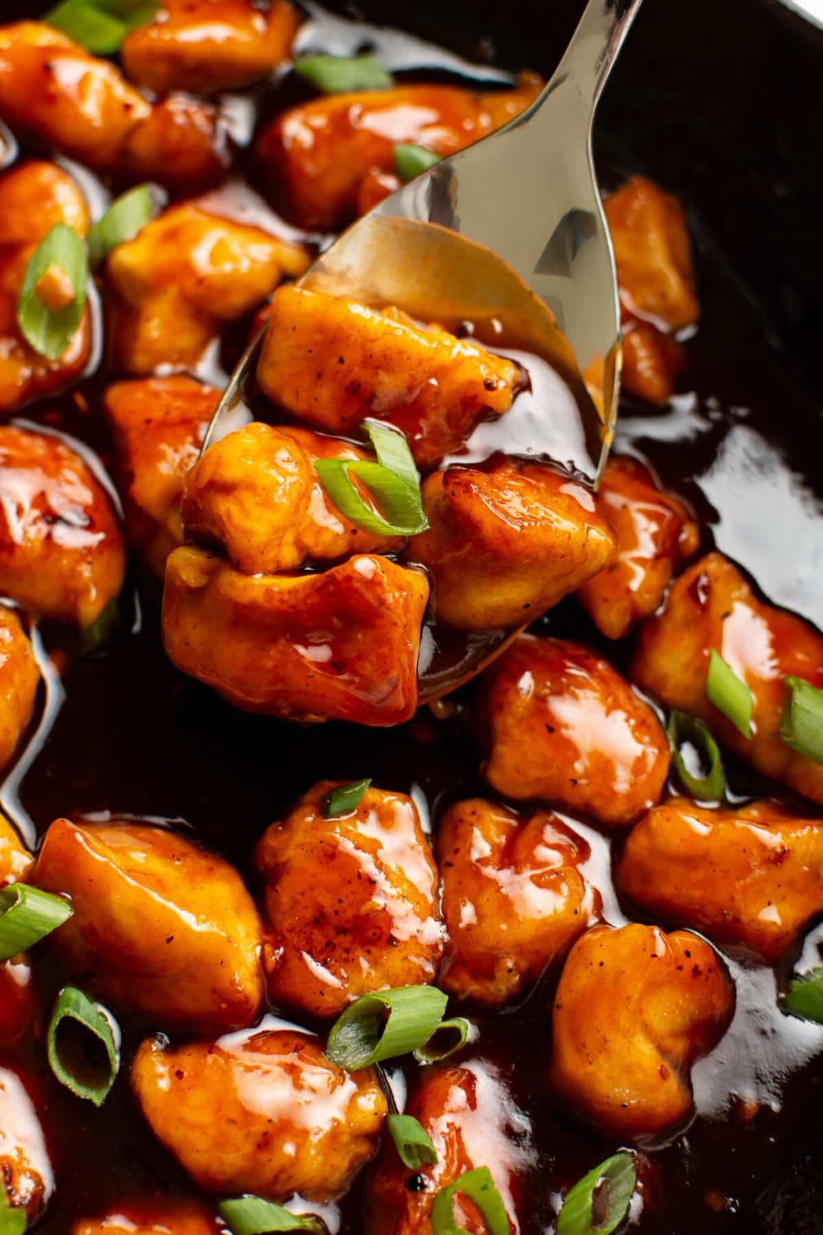 Feuriges Hähnchen 6 Nahaufnahme einer Pfanne mit Firecracker Hähnchen und einem Servierlöffel