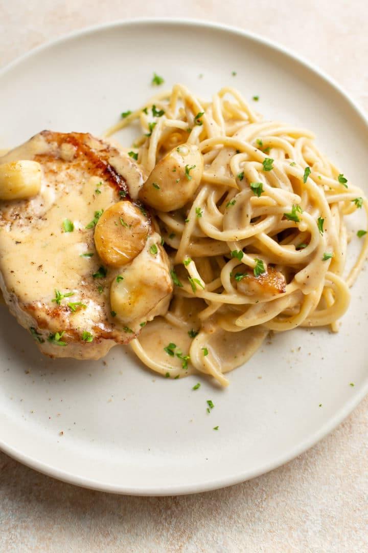 Cremige Knoblauch-Schweinekoteletts 7 cremige Knoblauch-Schweinekoteletts mit Spaghetti auf einem Teller