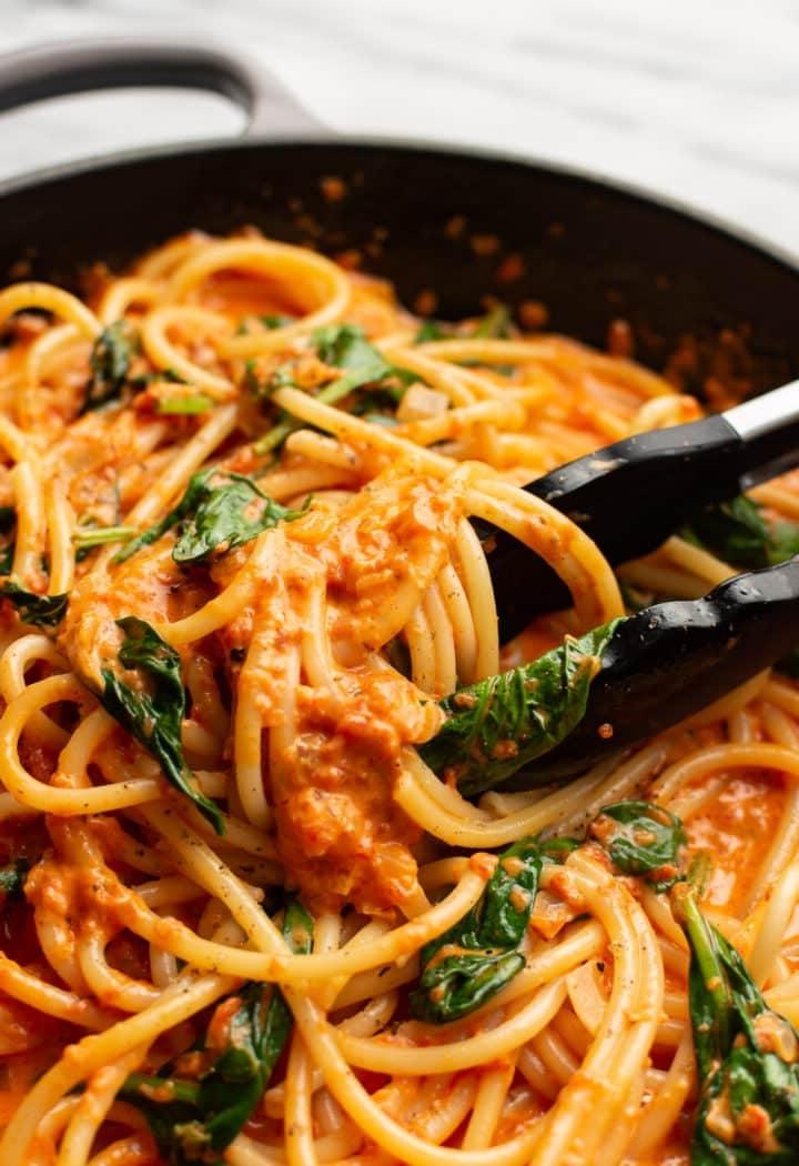 Cremige Pasta mit gerösteter roter Paprika 7 Nahaufnahme von Servierzangen in einer Pfanne mit gerösteter Paprika Pasta