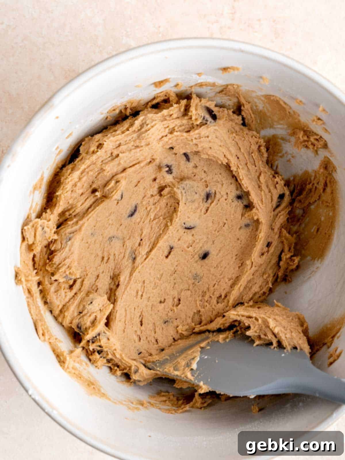 Sourdough chocolate chip cookie dough in a bowl with a rubber spatula.