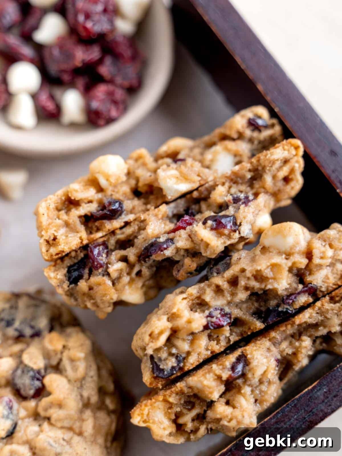 Oatmeal craisin cookies with white chocolate chips, one cut in half to reveal the chewy interior filled with oats, dried cranberries, and melted white chocolate.
