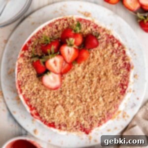 No Bake Strawberry Crunch Cheesecake 13 A vibrant slice of No-Bake Strawberry Crunch Cheesecake with layers visible and a bite taken out.