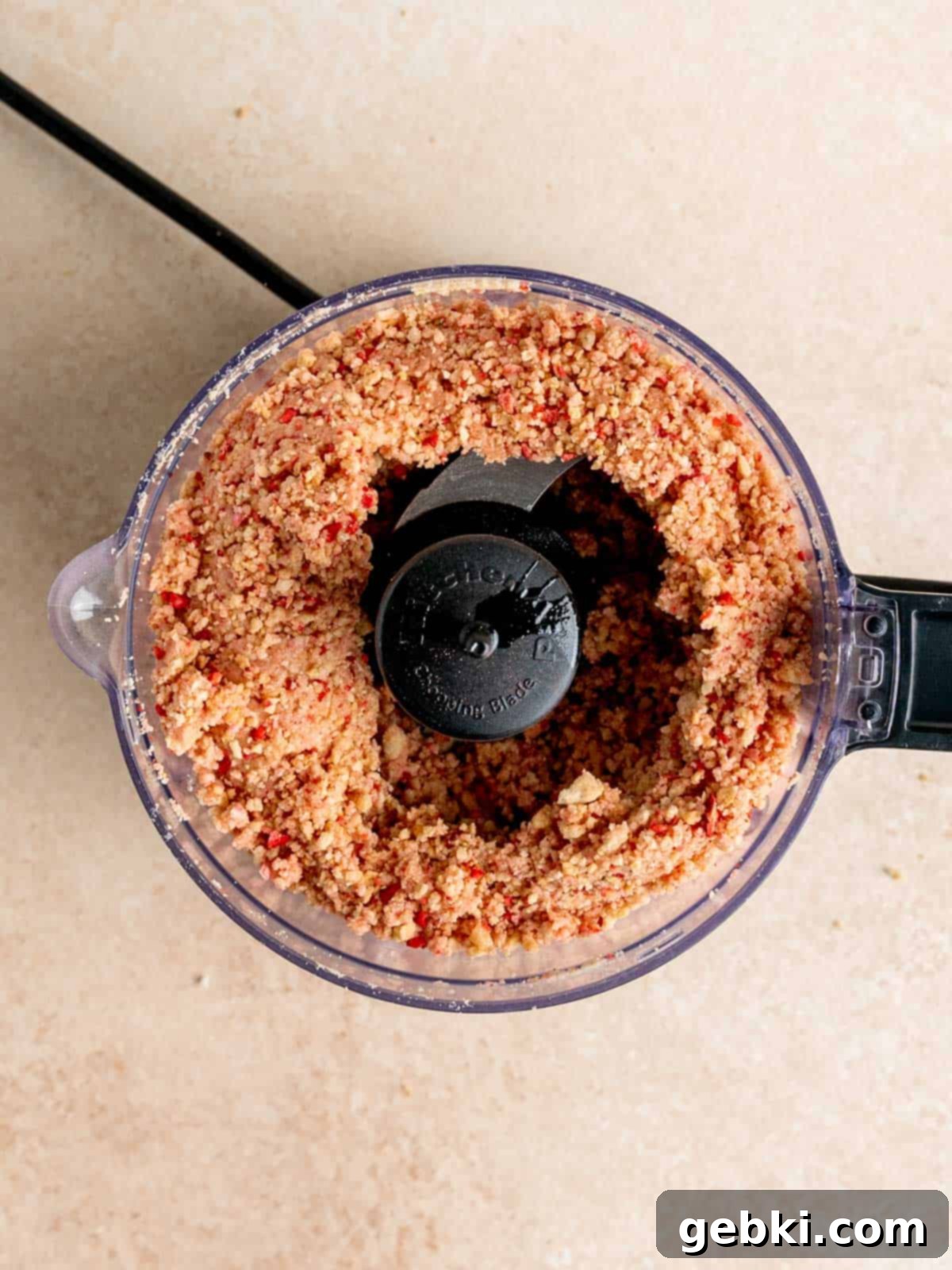 No Bake Strawberry Crunch Cheesecake 4 Golden Oreos and freeze-dried strawberries being processed in a food processor for the crust.