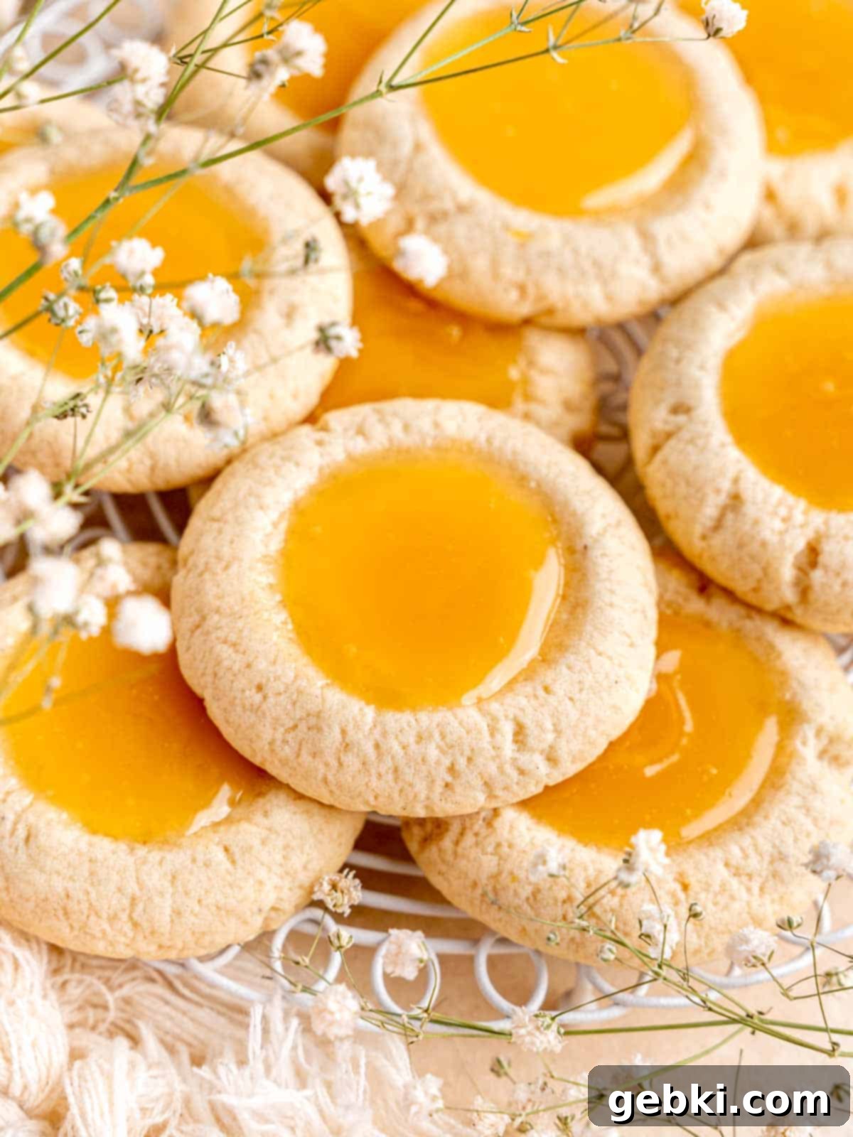 Simple Lemon Curd Thumbprint Cookies 9 Thumbprint cookies with lemon curd surrounded by little white flowers.
