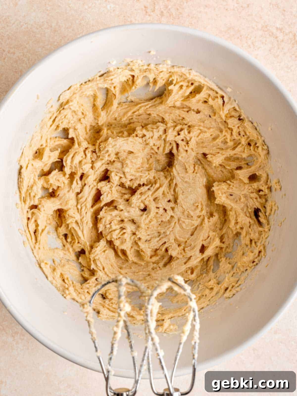 Creamed butter, sugars, egg, and vanilla extract mixed together in a bowl, creating a light and fluffy base.