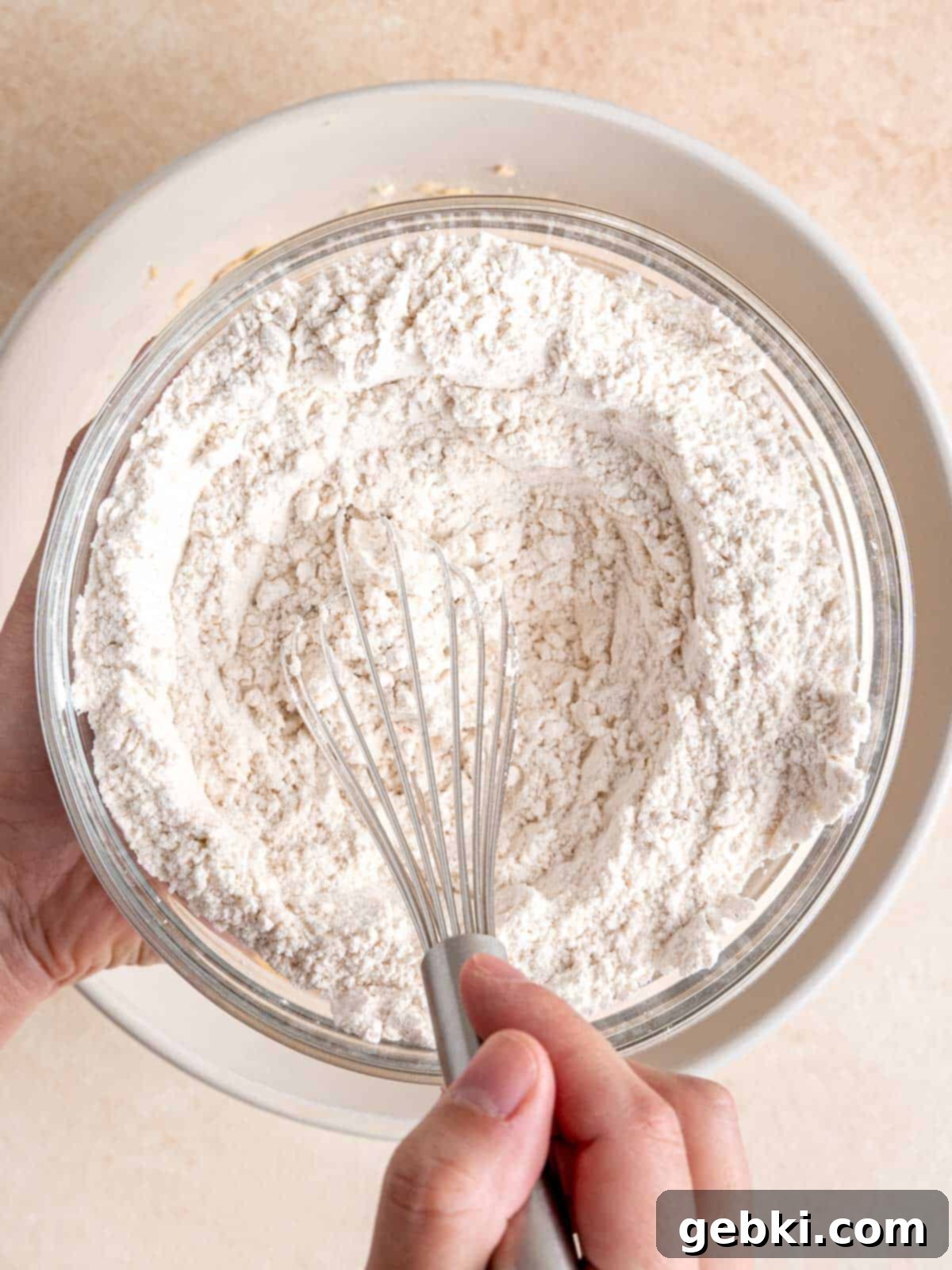 Flour, baking soda, and salt being whisked together in a separate bowl.