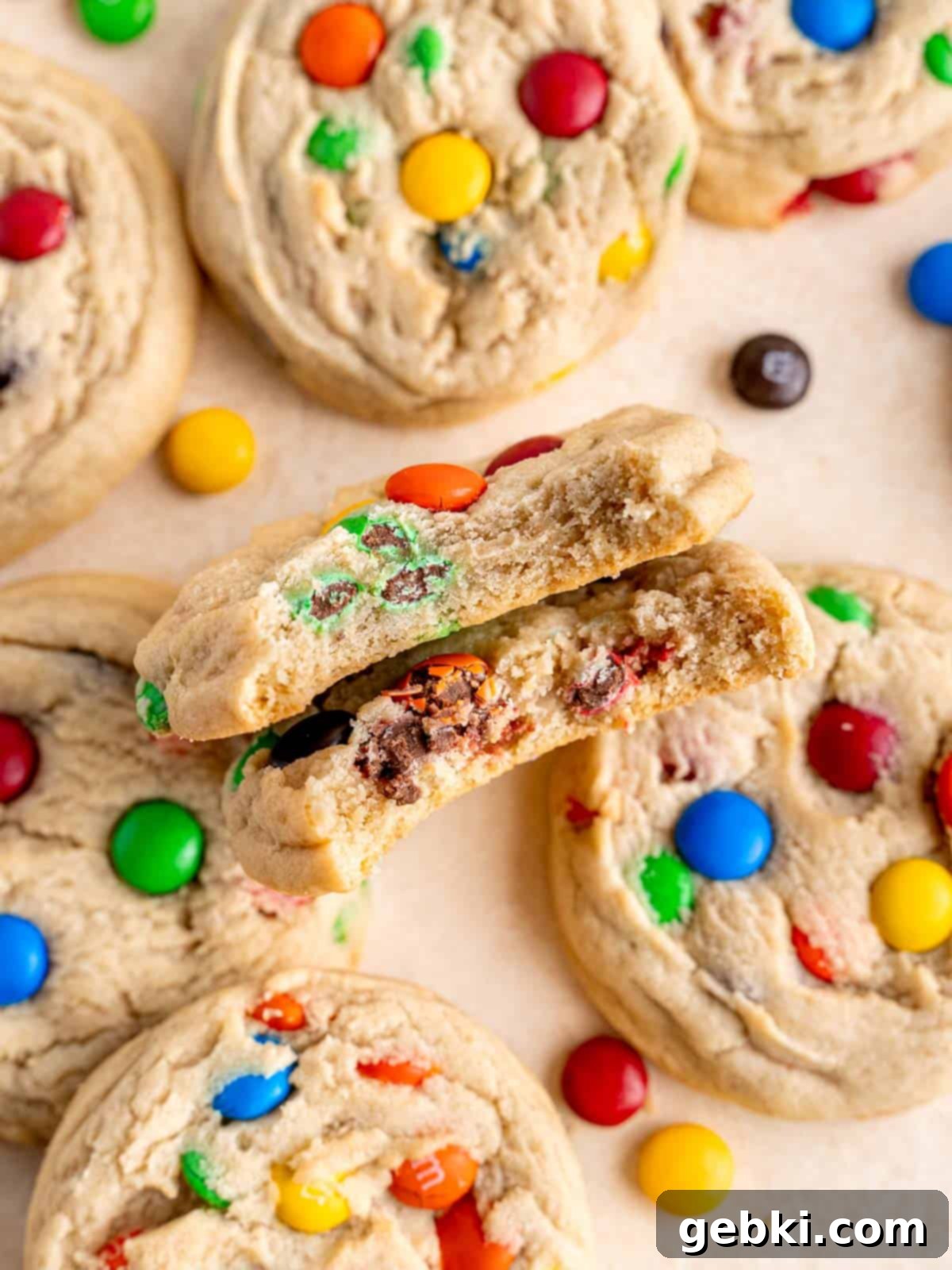 Two soft M&M sugar cookies with bites taken out of them, showing the chewy interior and chocolate candies.