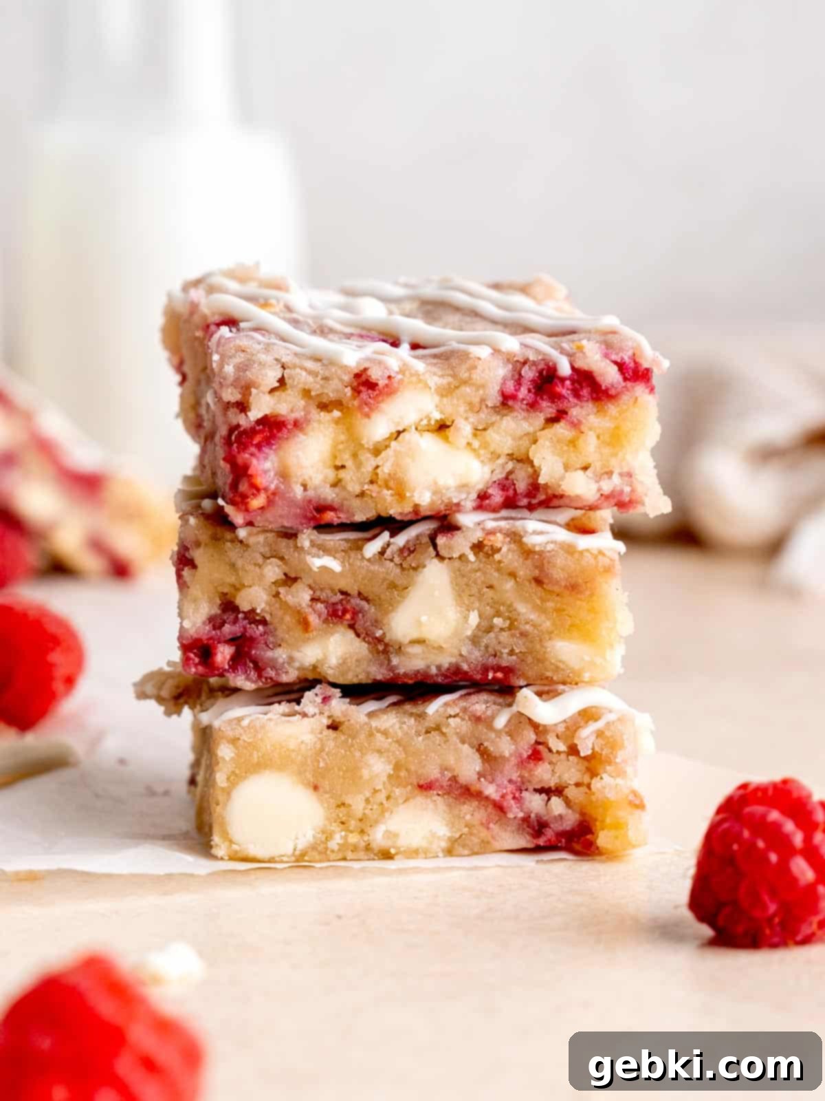 White Chocolate Raspberry Swirl Blondies 2 A perfectly stacked pile of freshly baked Raspberry and White Chocolate Blondies, showing their rich, fudgy texture and embedded red raspberries and white chocolate chunks.