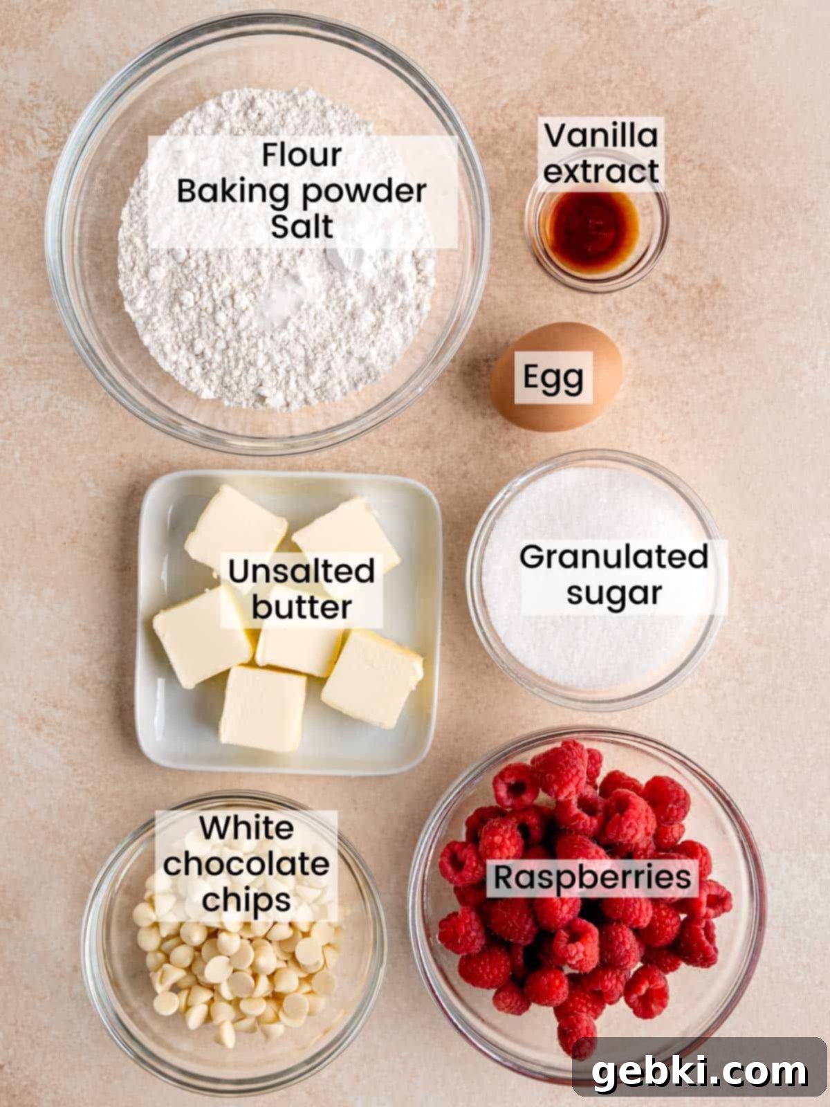 White Chocolate Raspberry Swirl Blondies 3 A flat lay photograph showcasing all the ingredients required for making white chocolate blondies with raspberries, neatly arranged on a white surface.