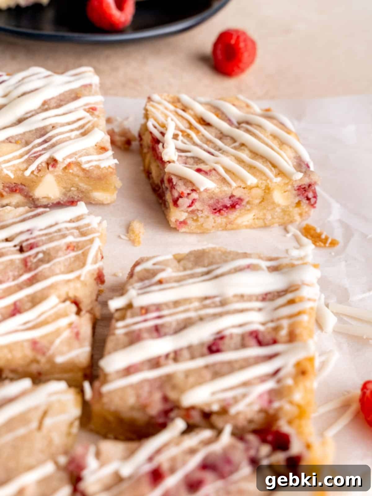 White Chocolate Raspberry Swirl Blondies 8 A close-up shot of freshly baked Raspberry White Chocolate Blondies, drizzled with extra melted white chocolate on top, highlighting the vibrant raspberries.
