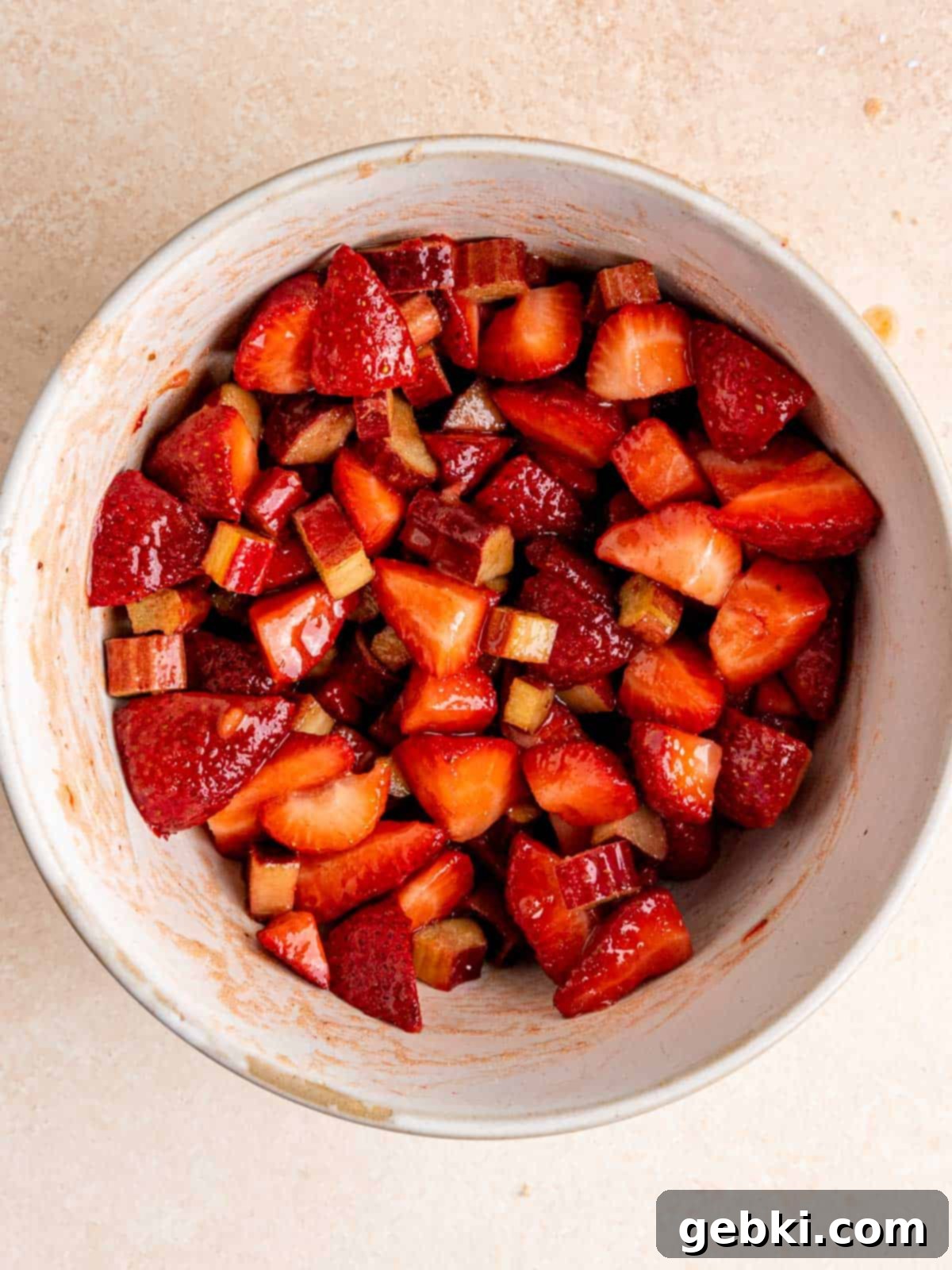 Chopped fresh strawberries and rhubarb mixed with brown sugar, cornstarch, and lemon juice in a large bowl, showing the vibrant fruit filling.