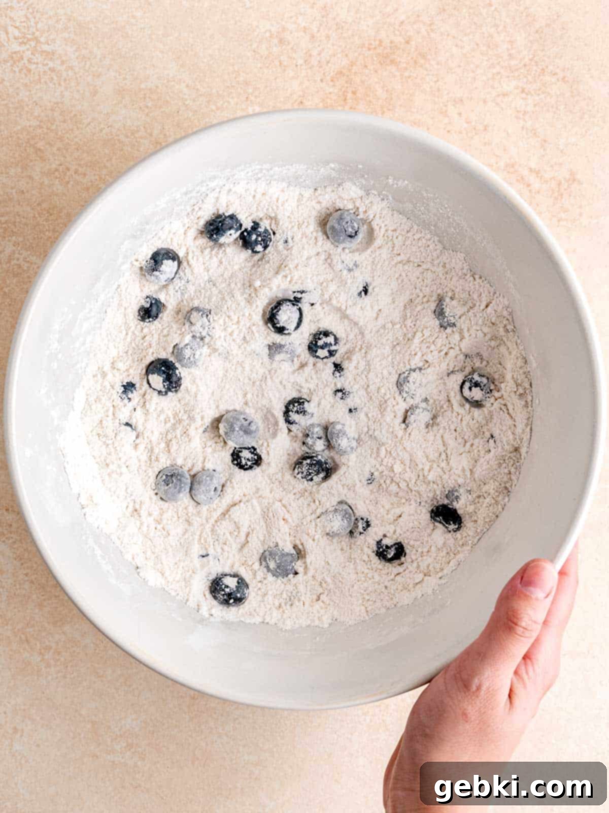 Ultimate Sourdough Discard Blueberry Muffins 4 Tossing blueberries into a flour mixture.