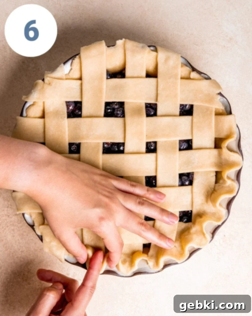 Aromatic Blueberry Delight 11 Pressing down on the crimped pie crust edge to secure it against the pie dish.