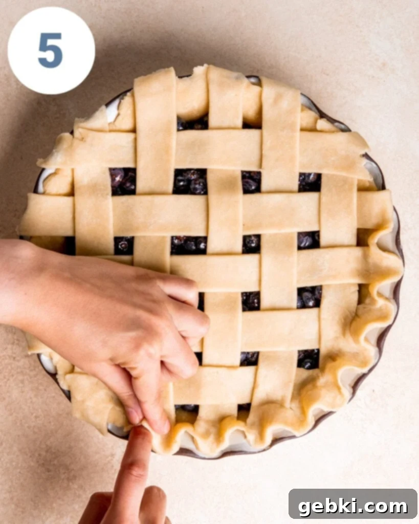 Aromatic Blueberry Delight 10 Close-up of fingers gently crimping the edge of a pie crust, creating a decorative border.