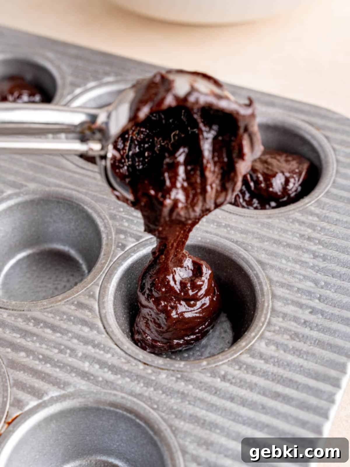 Peanut Butter Cup Brownie Bites 6 Scooping brownie batter into a mini muffin pan.