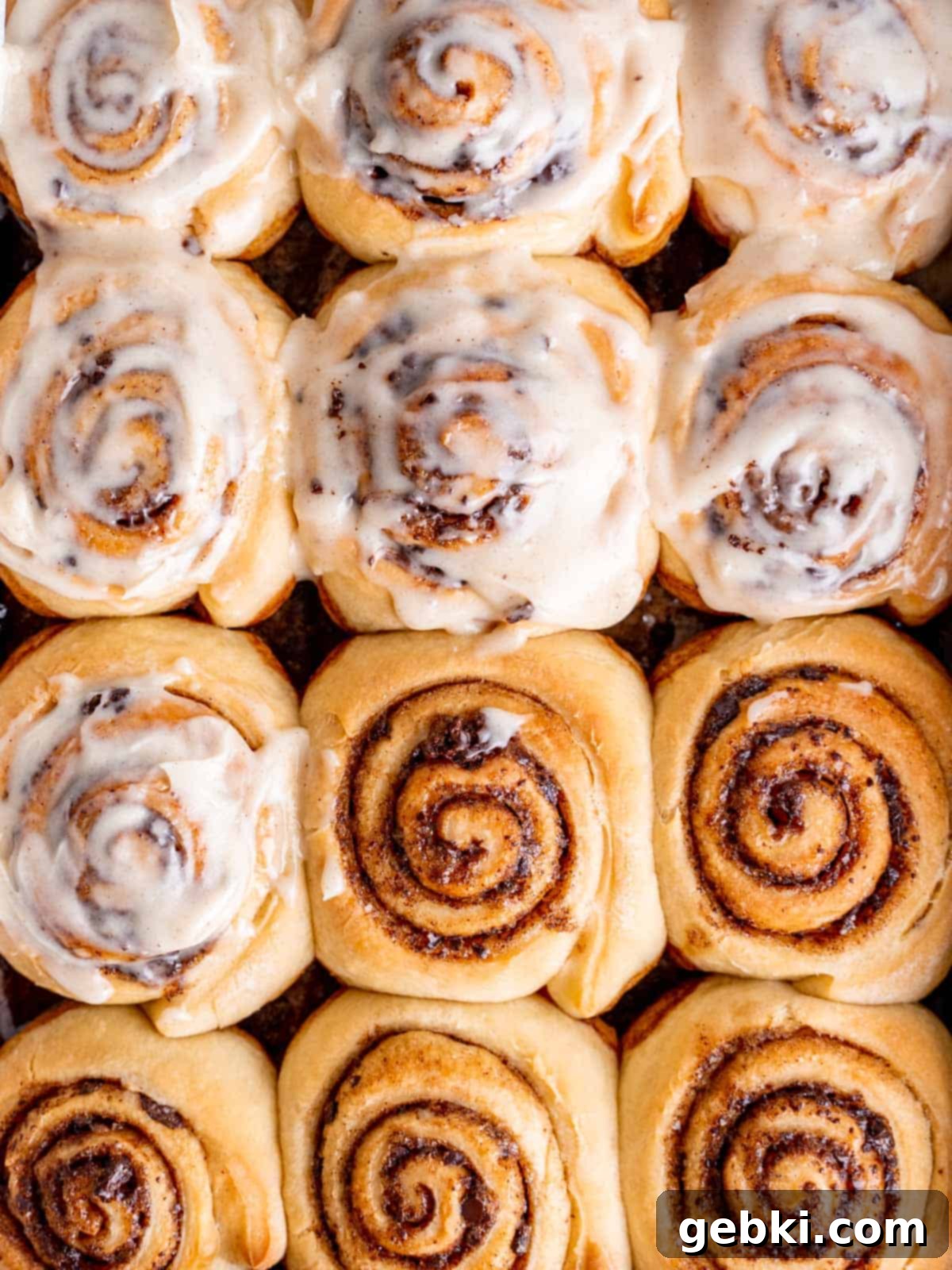 Snickerdoodle Rolls up close, some frosted and some unfrosted, showing their soft texture and flavorful swirl.