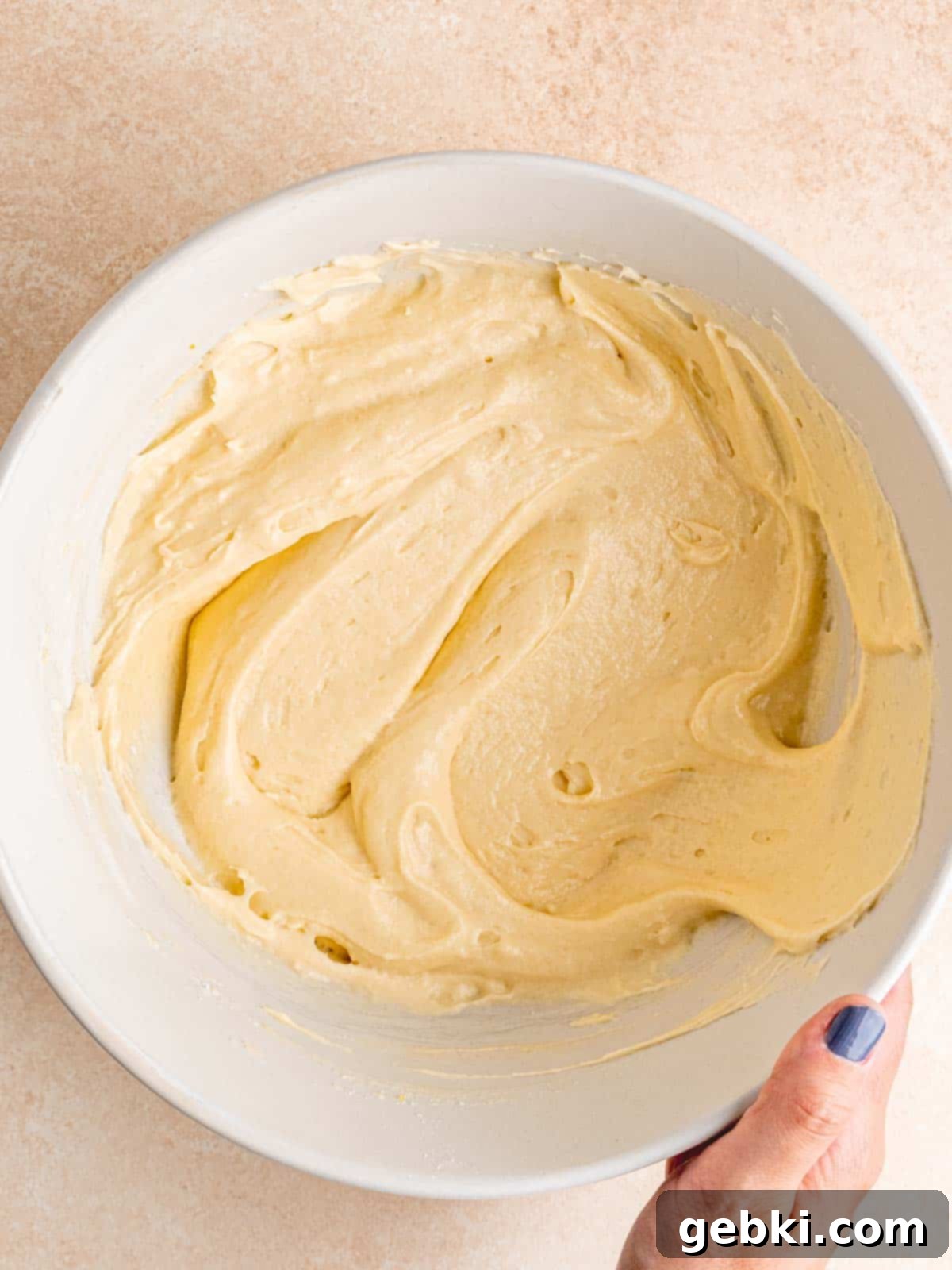 The smooth, pale yellow almond cupcake batter in a large mixing bowl, perfectly blended and ready for portioning.