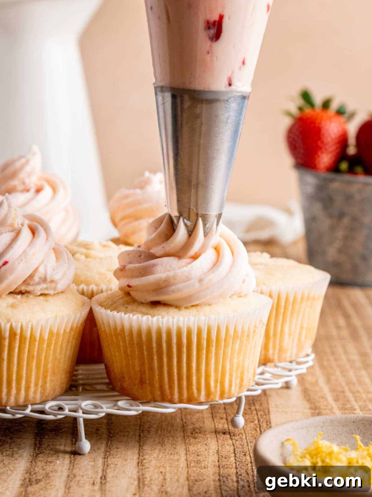 Zesty Lemon Cupcakes with Strawberry Filling 9 Piping lemon strawberry buttercream onto lemon cupcakes using a large star piping tip, creating beautiful swirls.