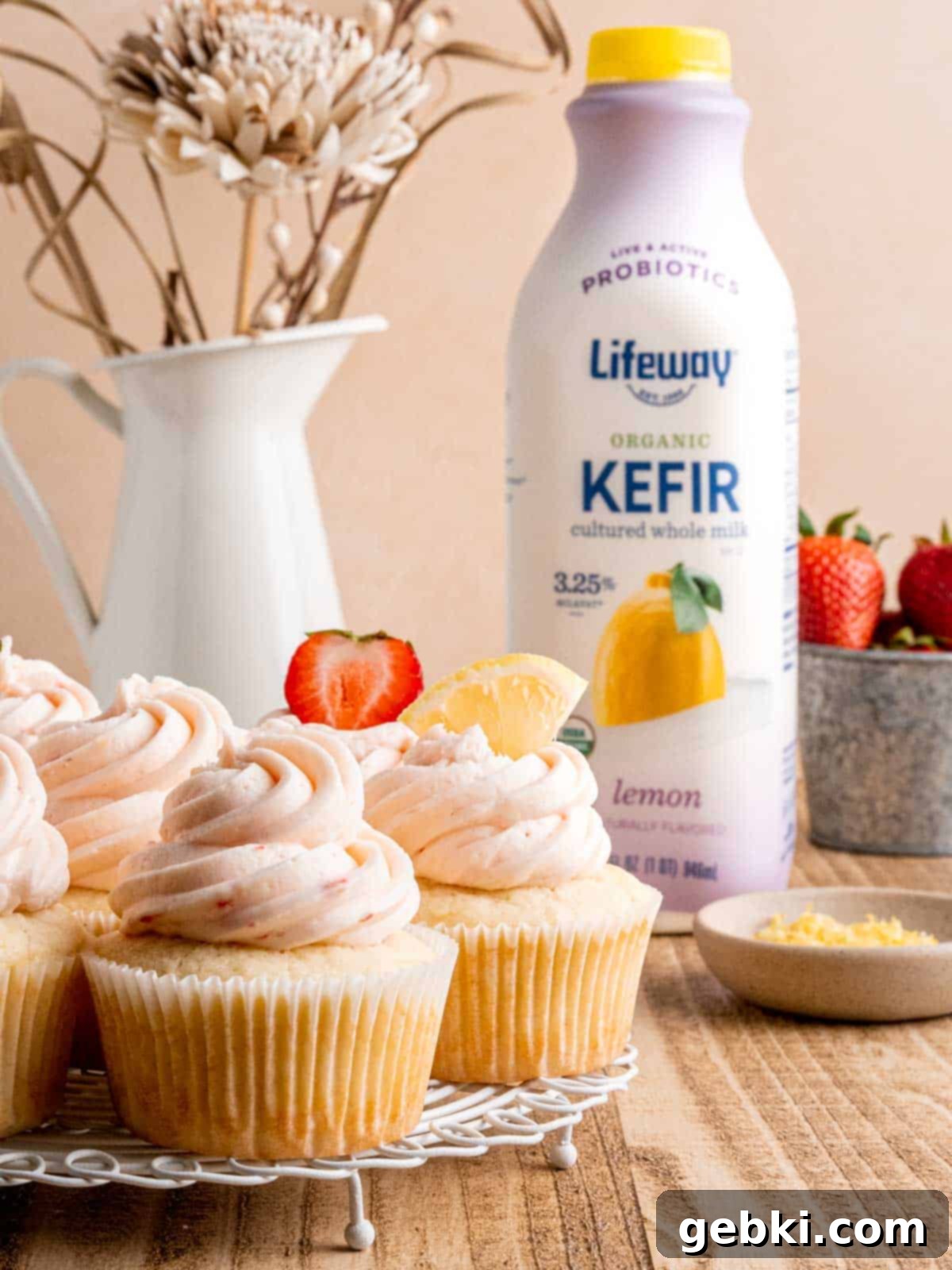 Zesty Lemon Cupcakes with Strawberry Filling 10 Beautifully frosted strawberry lemon cupcakes cooling on a wire rack, with a bottle of Lifeway kefir in the background.