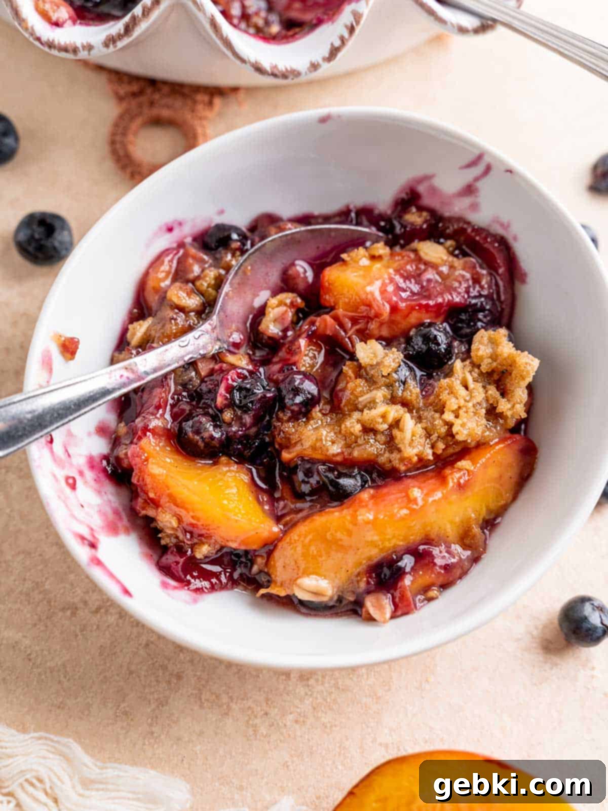 Sweet Summer Blueberry Peach Crisp 8 A bowl of warm blueberry peach crisp topped with a dollop of vanilla ice cream, ready to be enjoyed.