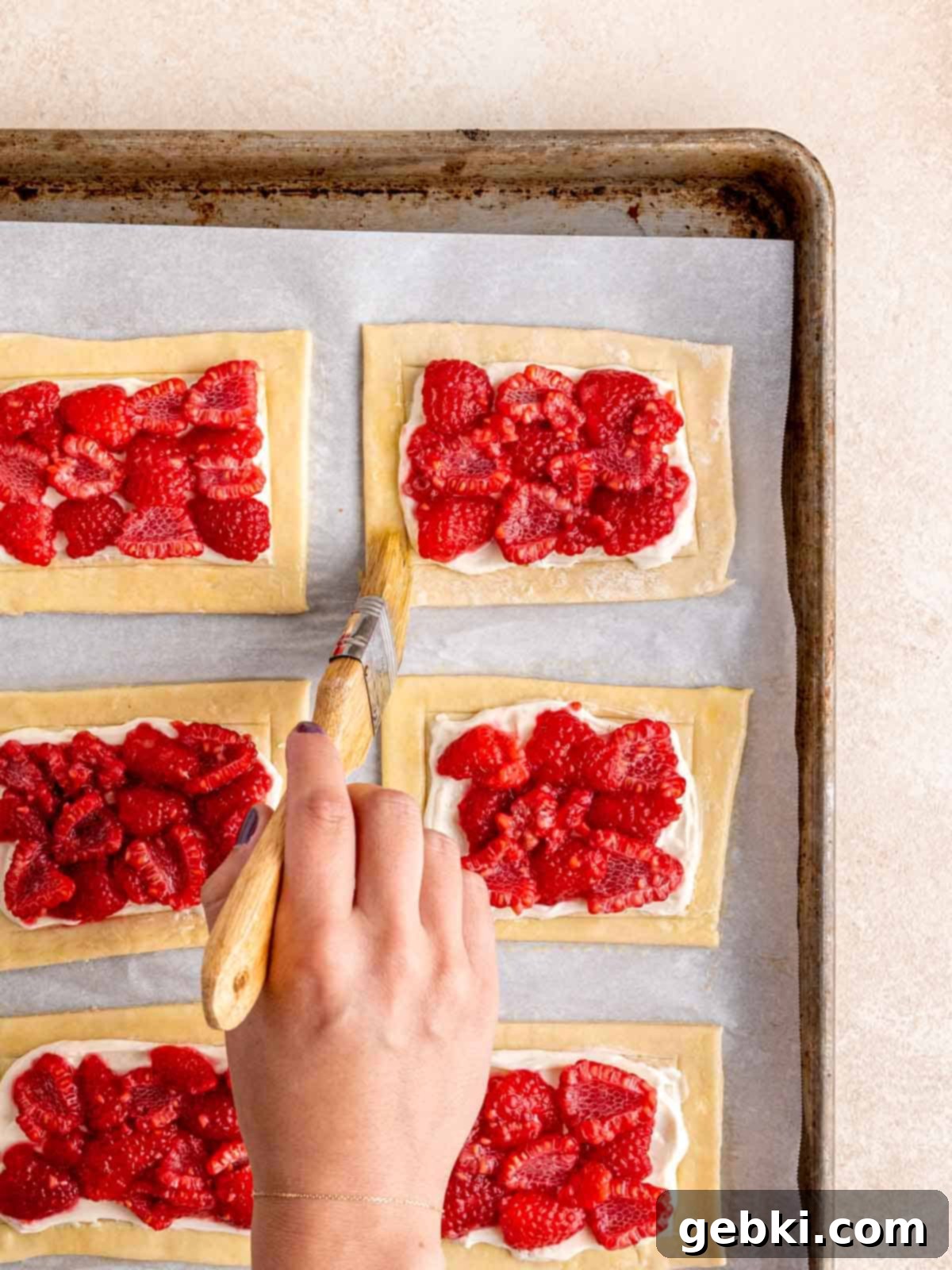 Easy Raspberry Cream Cheese Danish 8 Brushing egg wash on the edges of unbaked raspberry danishes.