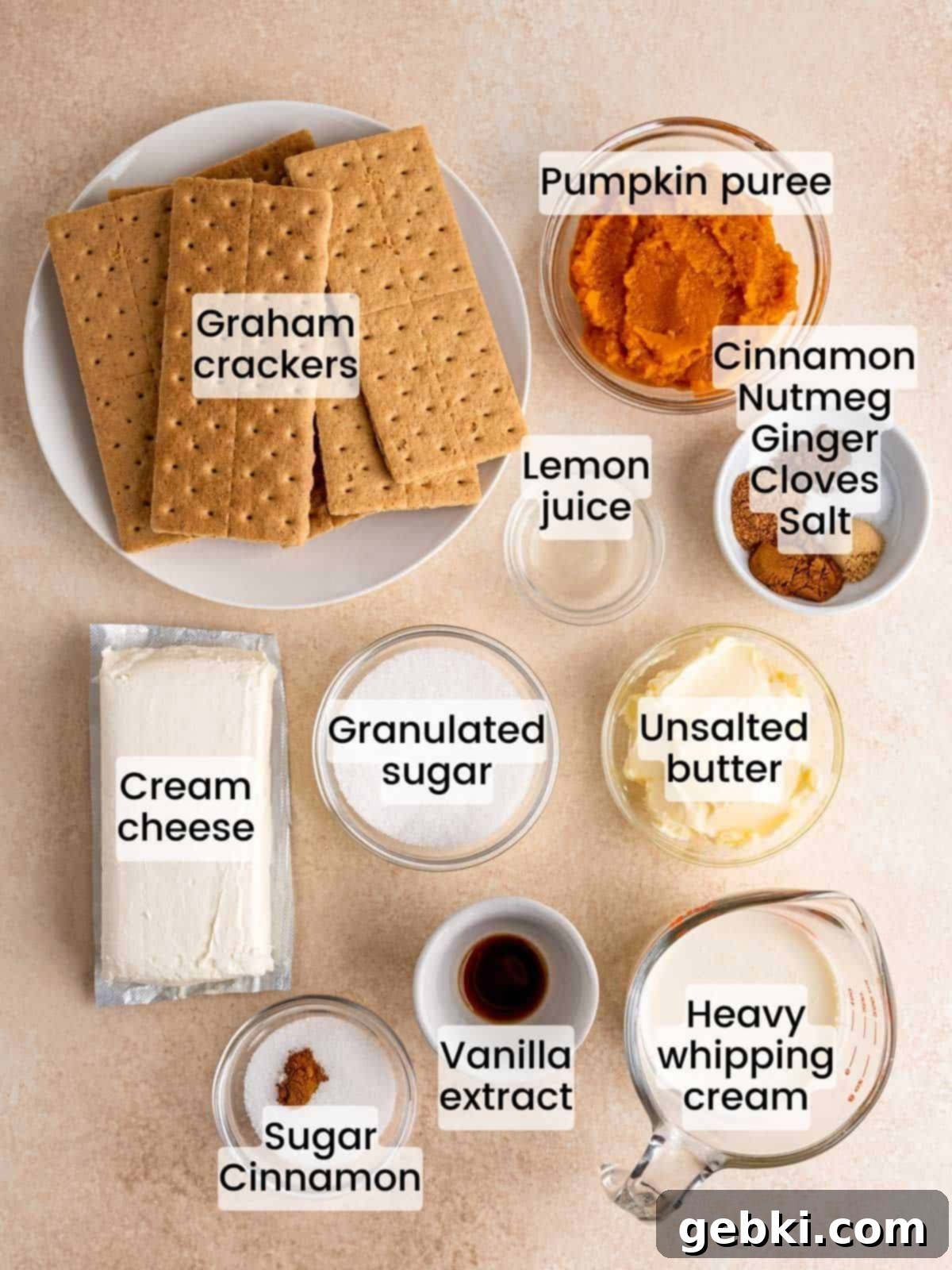 A selection of ingredients laid out on a table, including graham crackers, pumpkin puree, cream cheese, and spices, all ready to make no bake mini pumpkin cheesecakes.