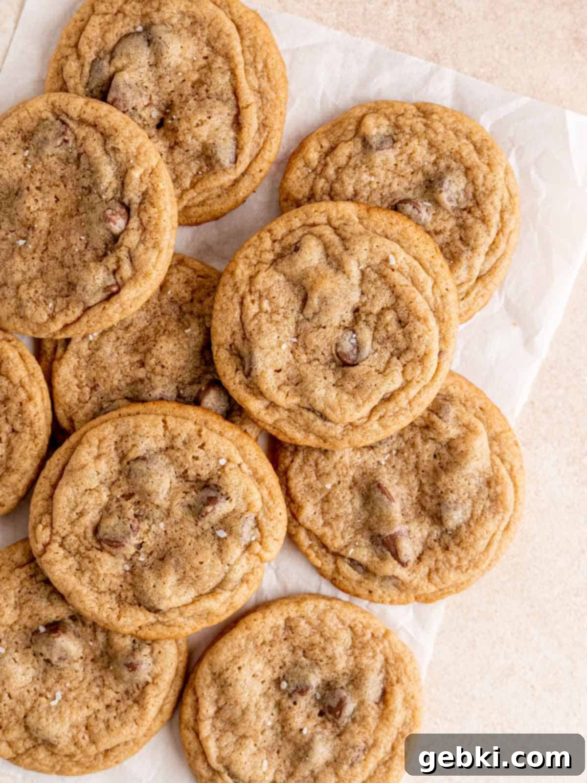 Chewy malted chocolate chip cookies on parchment paper, fresh out of the oven.