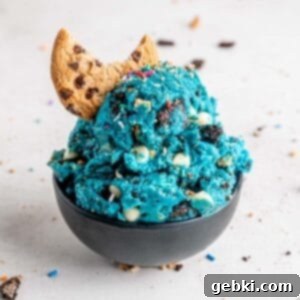 Scoops of edible cookie monster cookie dough with a chocolate chip cookie in a bowl.