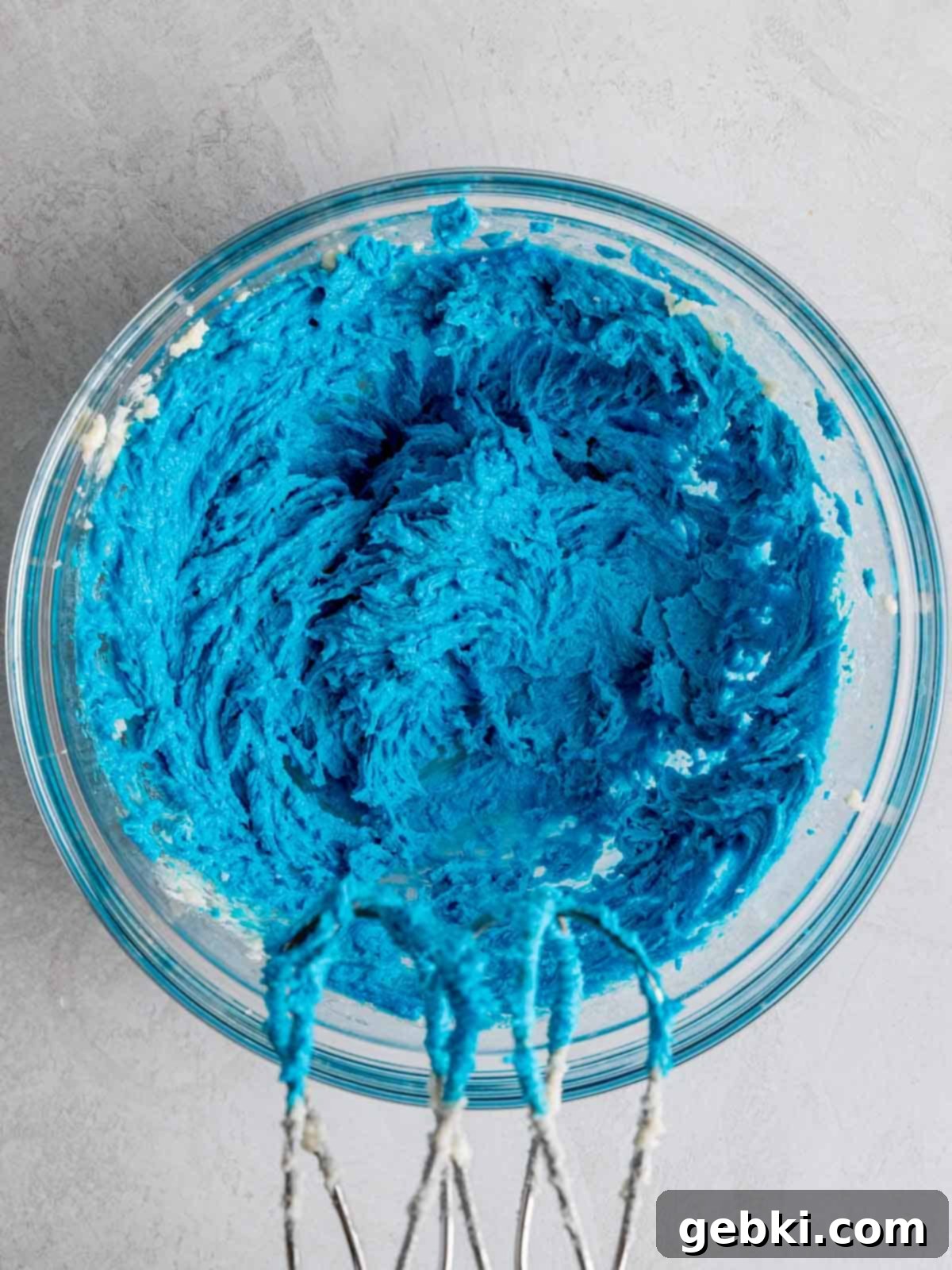 Butter, sugar, blue food coloring, and vanilla extract mixed in a bowl.