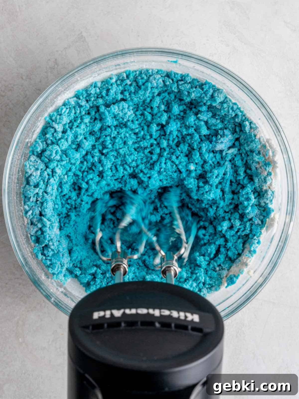 Mixing heat treated flour and salt into blue colored edible cookie dough.