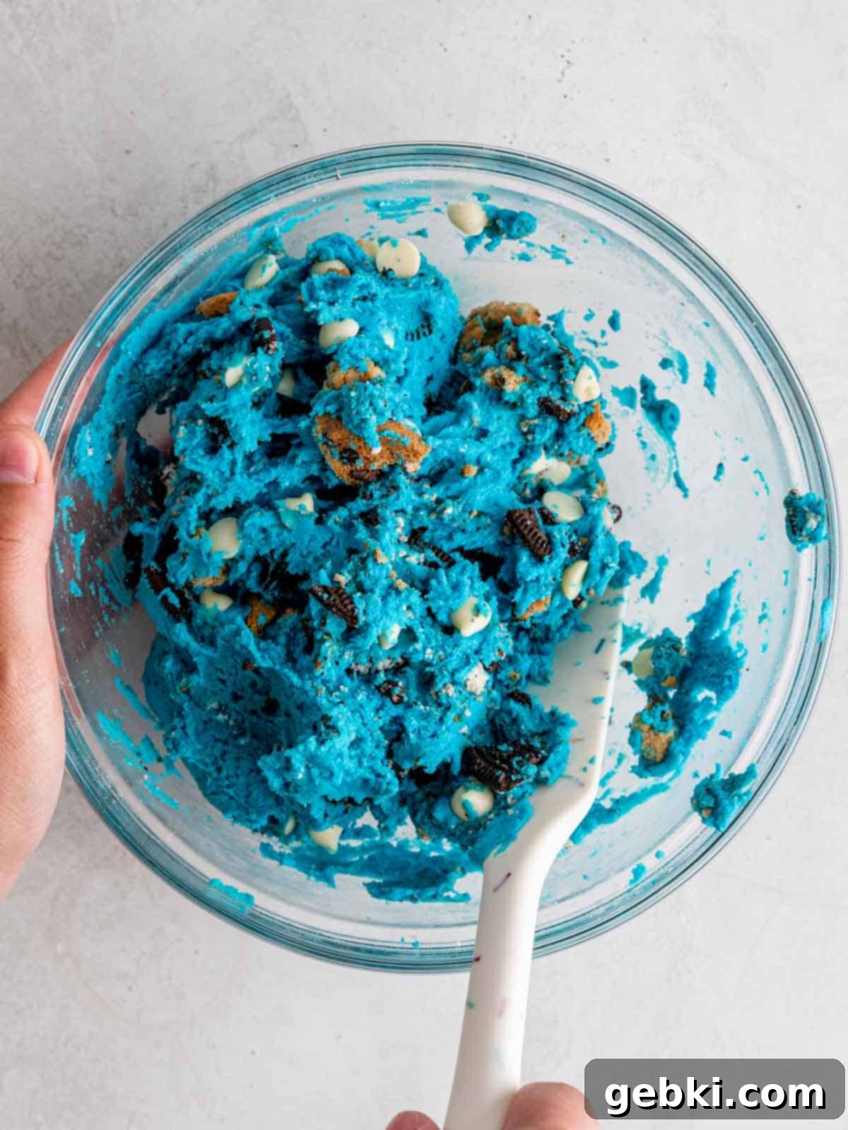 Folding crushed Oreos, Chips Ahoy chocolate chip cookies, and white chocolate chips into edible cookie dough.