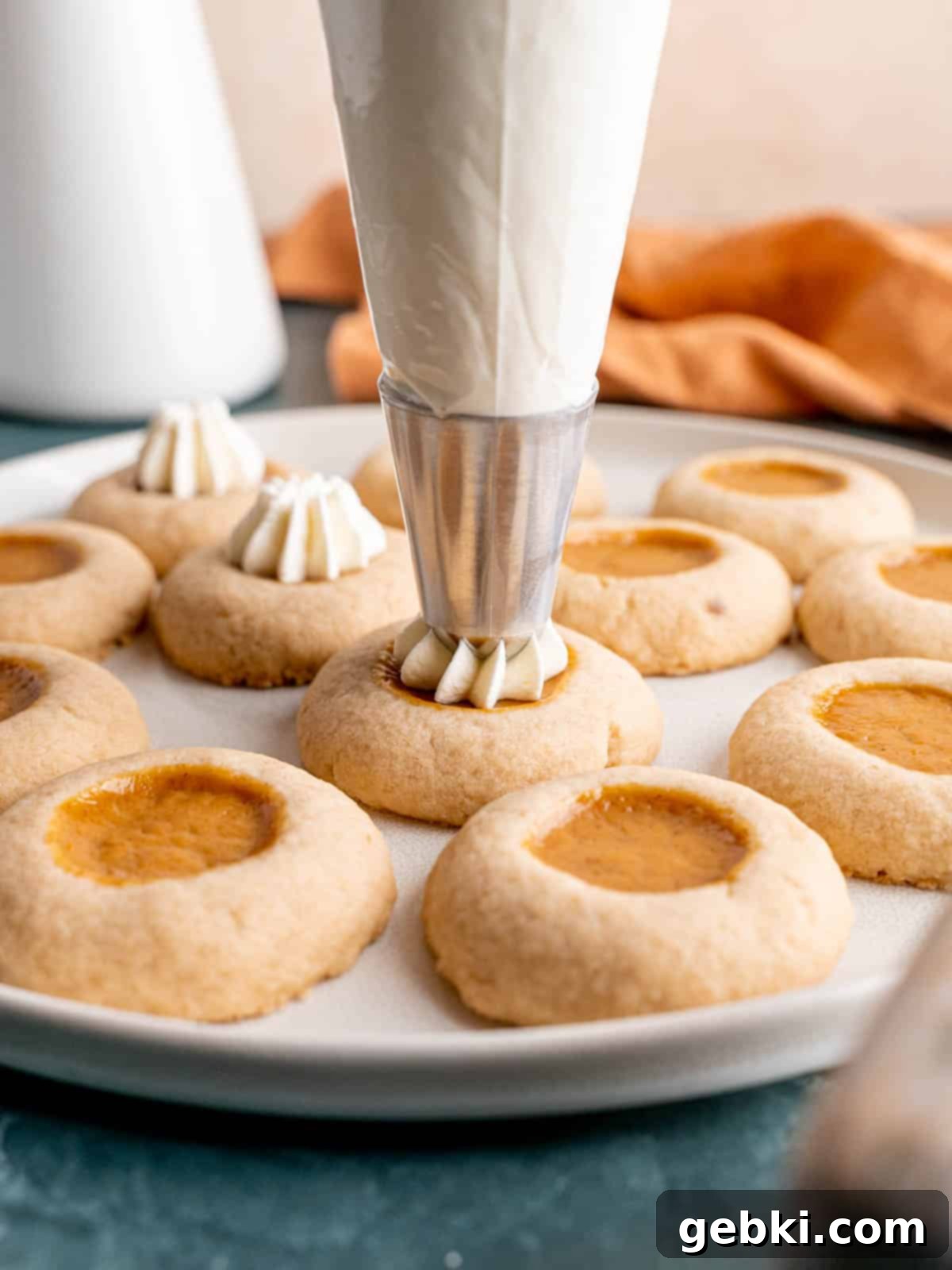 Piping whipped cream on a pumpkin pie cookie.