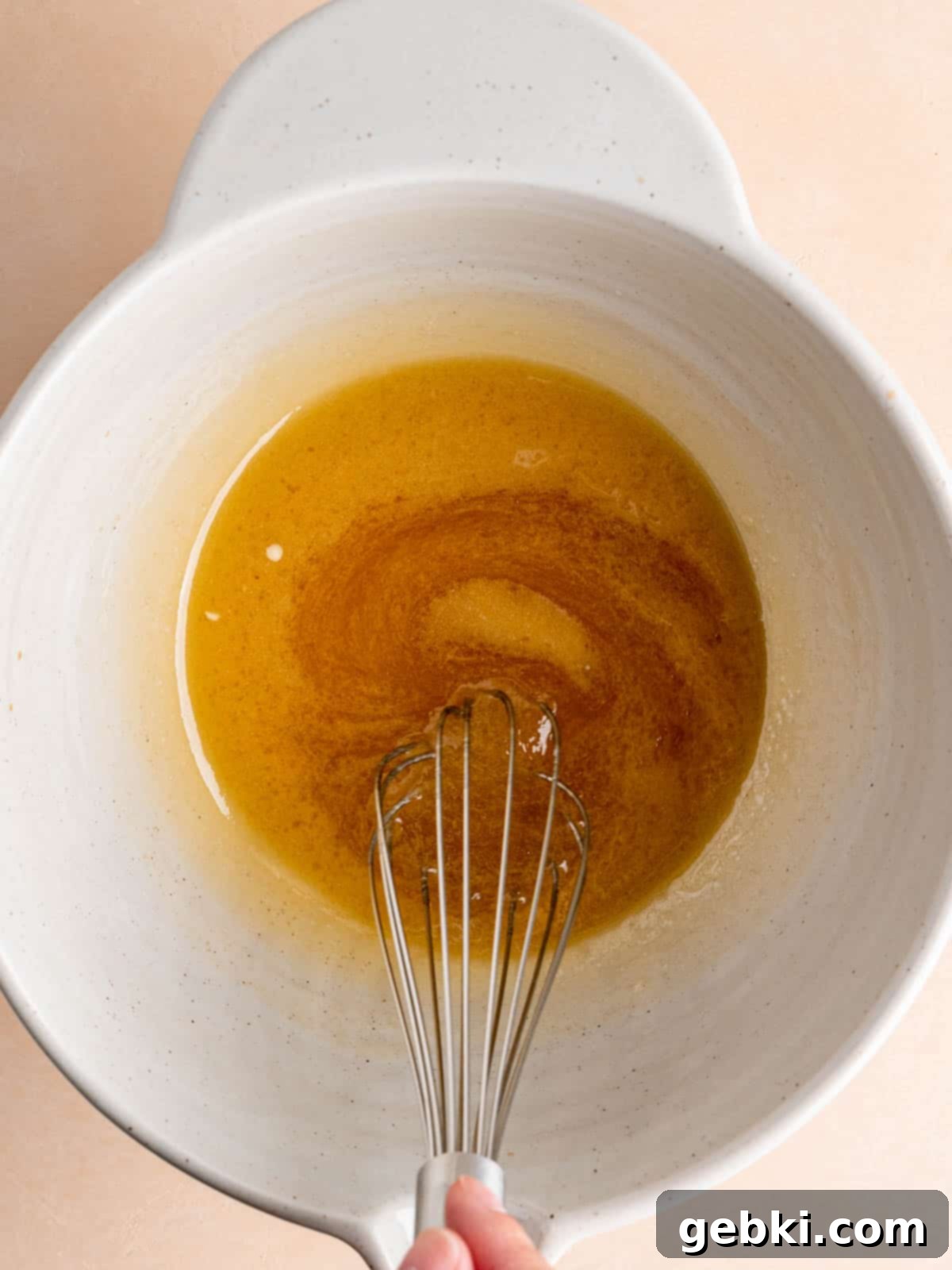 Golden Honey Banana Loaf 5 A whisk blending melted butter and golden honey in a large glass bowl.