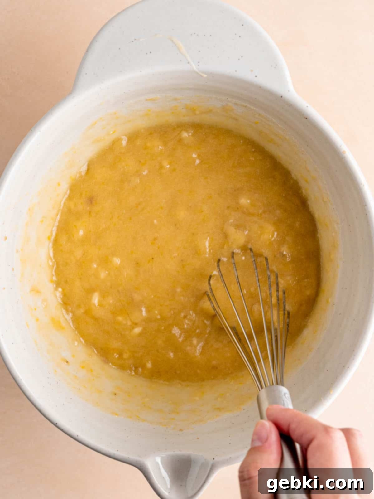 Golden Honey Banana Loaf 6 All wet ingredients for honey banana bread, including mashed bananas, eggs, vanilla, butter, and honey, are being whisked together in a bowl.