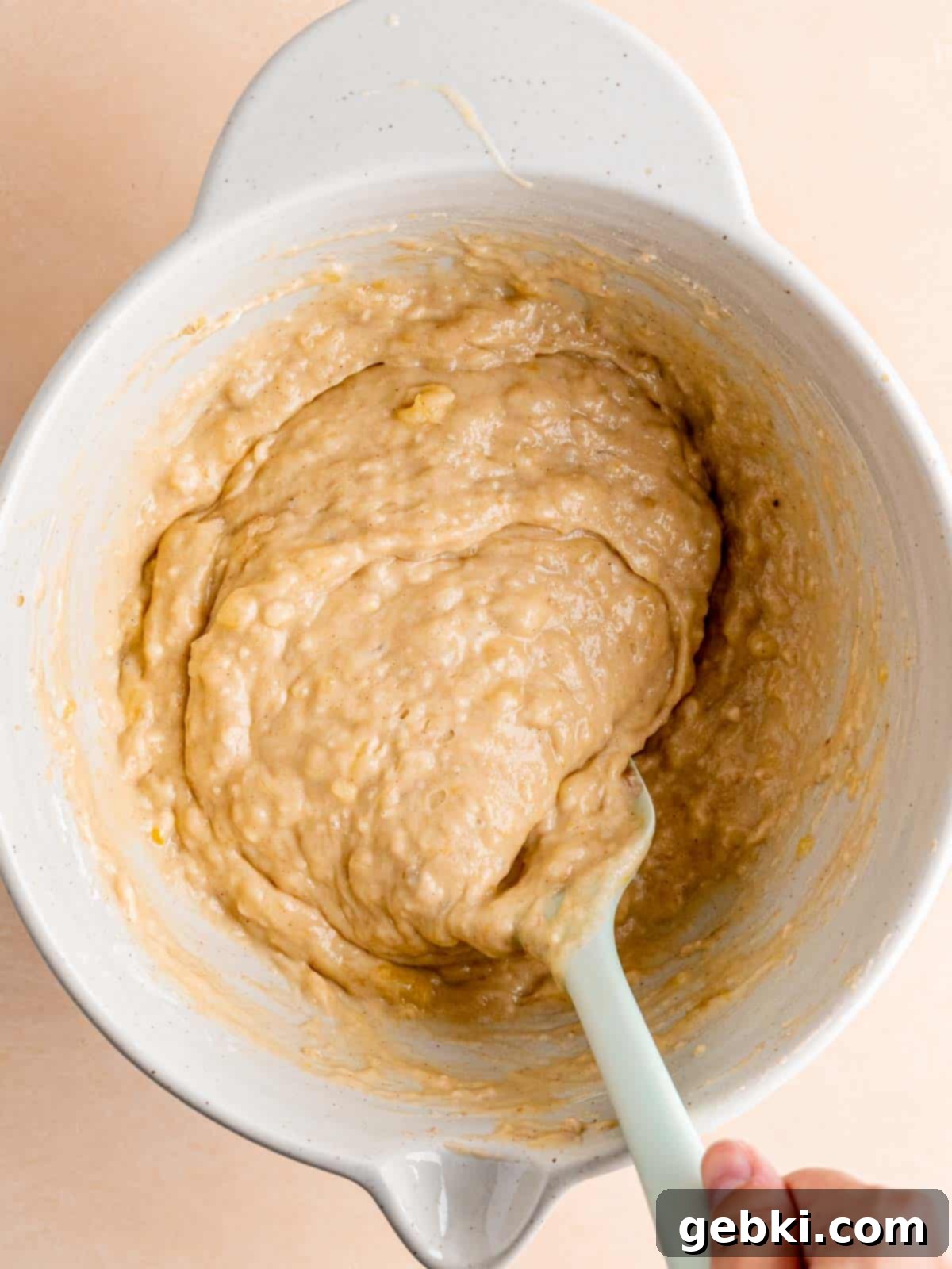 Golden Honey Banana Loaf 7 The finished honey banana bread batter, thick and golden brown, in a mixing bowl with a spatula.