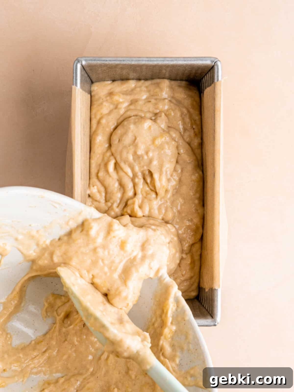 Golden Honey Banana Loaf 8 Thick honey banana bread batter being poured into a parchment paper-lined loaf pan, ready for baking.