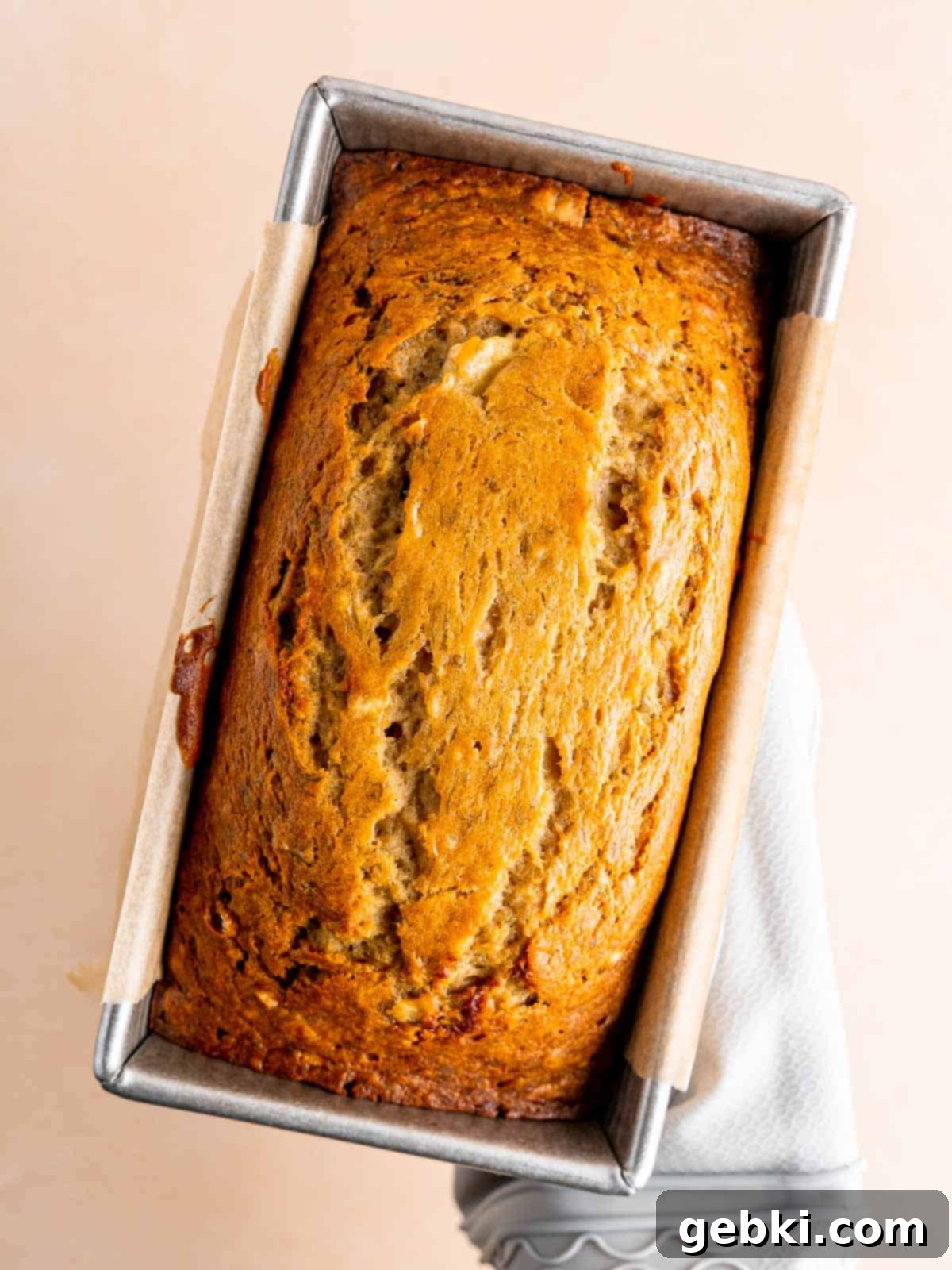 Golden Honey Banana Loaf 9 A freshly baked, golden brown honey banana bread loaf cooling in a parchment paper-lined loaf pan.