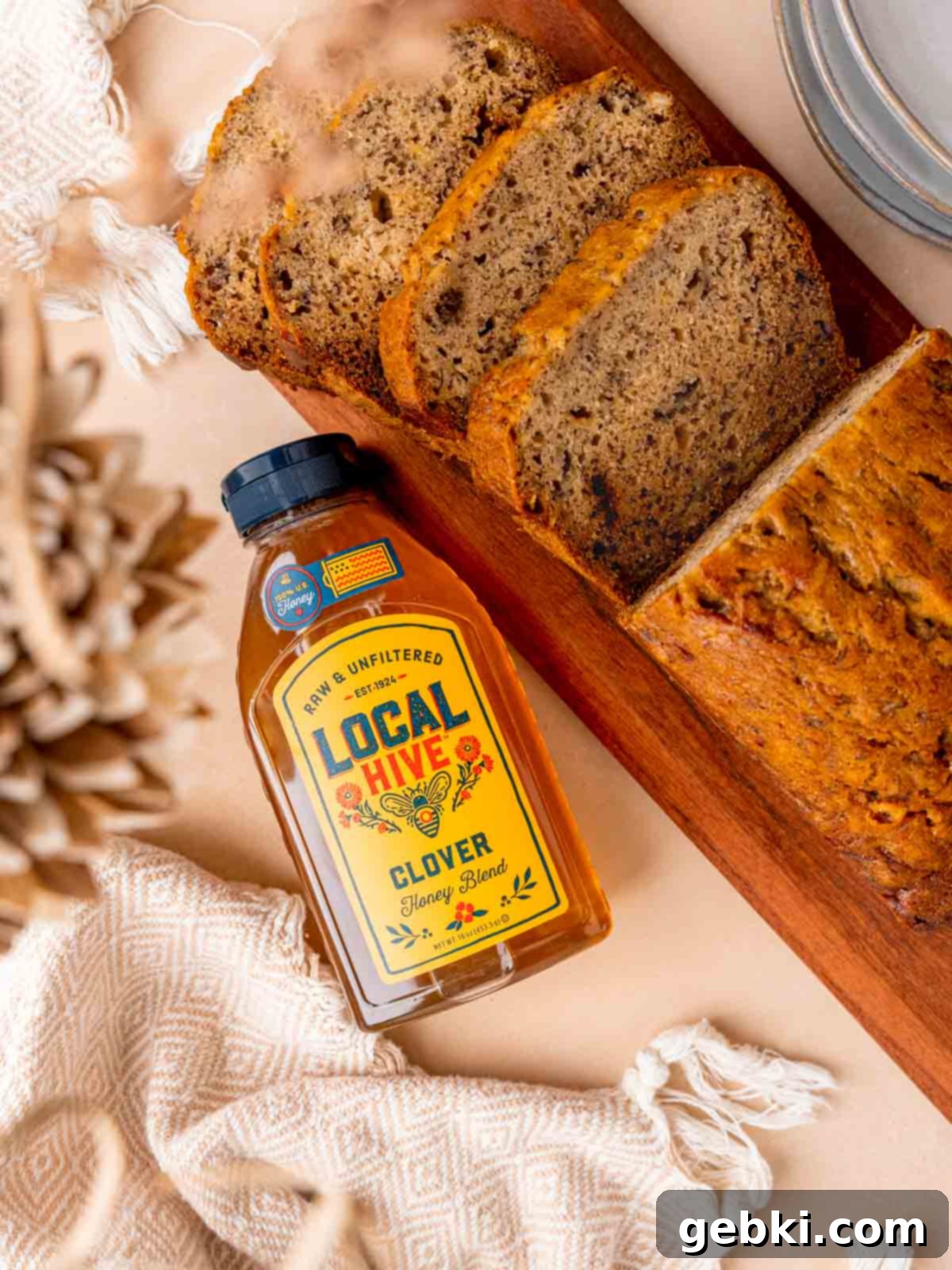 Golden Honey Banana Loaf 10 Two slices of golden-brown honey banana bread next to a bottle of Local Hive Honey, showcasing the delicious pairing.