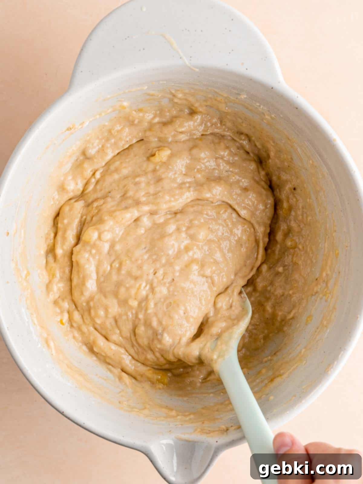Cinnamon Swirl Banana Bread Muffins 5 Mixing banana bread wet ingredients in a bowl with a whisk.