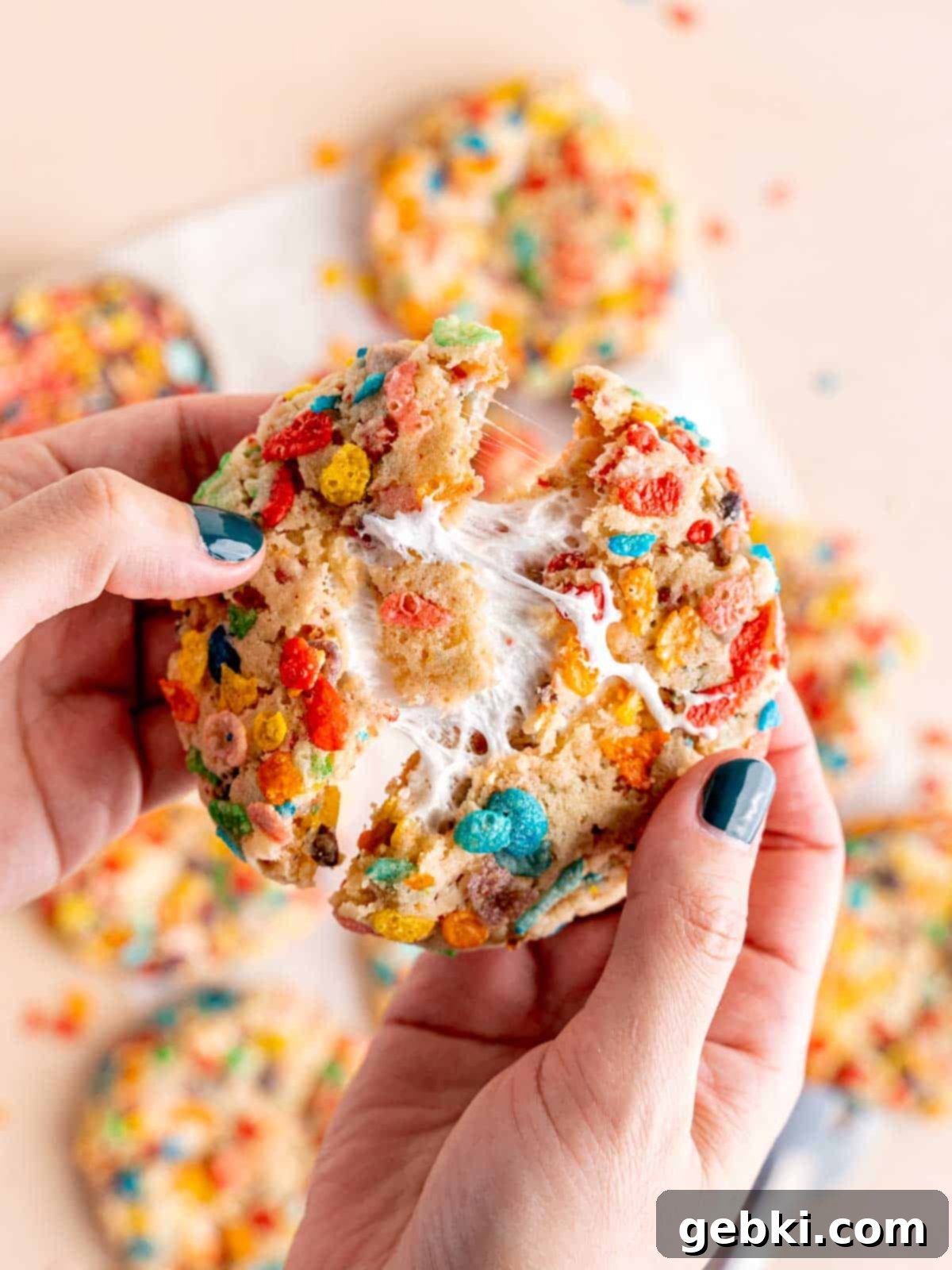 Pulling a Fruity Pebble cookie in half to show the marshmallow filling.