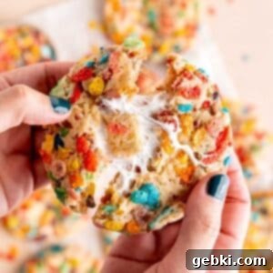 Pulling a Fruity Pebble cookie in half to show the marshmallow filling.