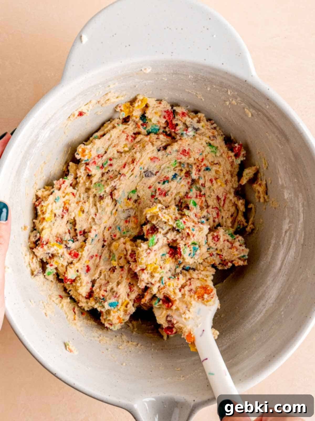Fruity Pebble cookie dough in a bowl with a spatula.